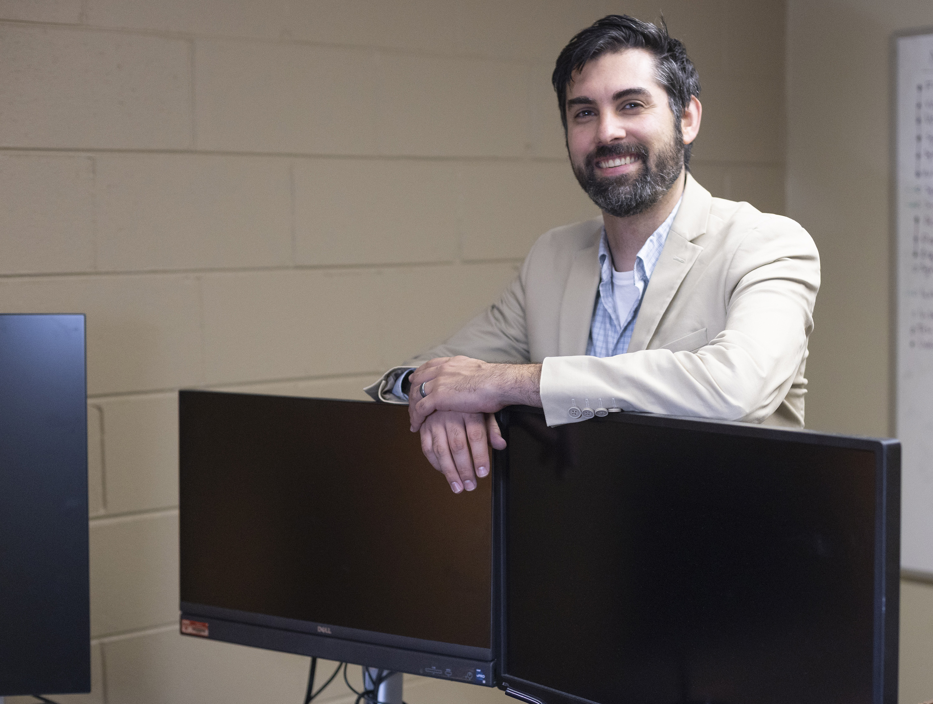 andrew madsen standing next to computers in his office