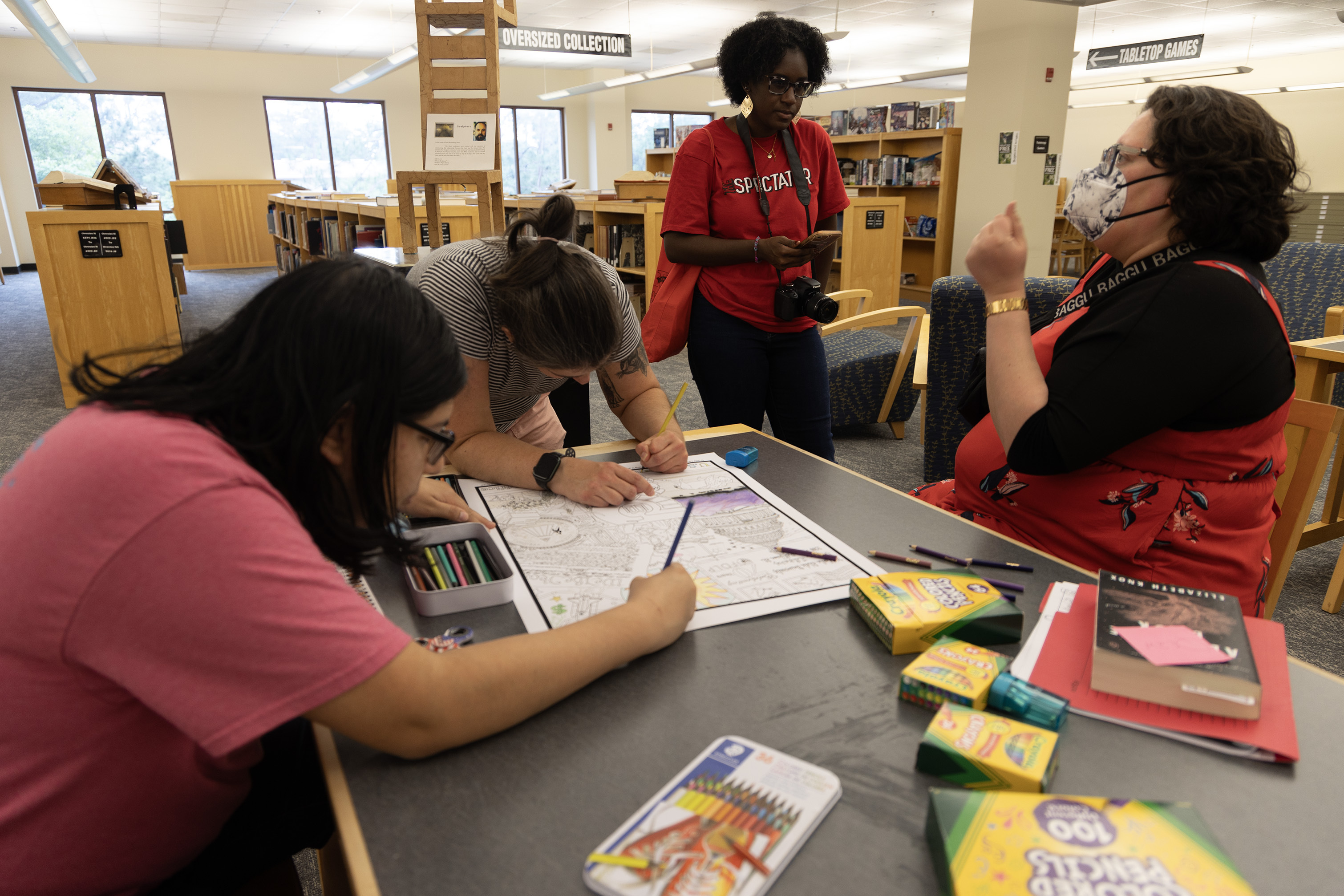 a group of people gathered around a table coloring and talking