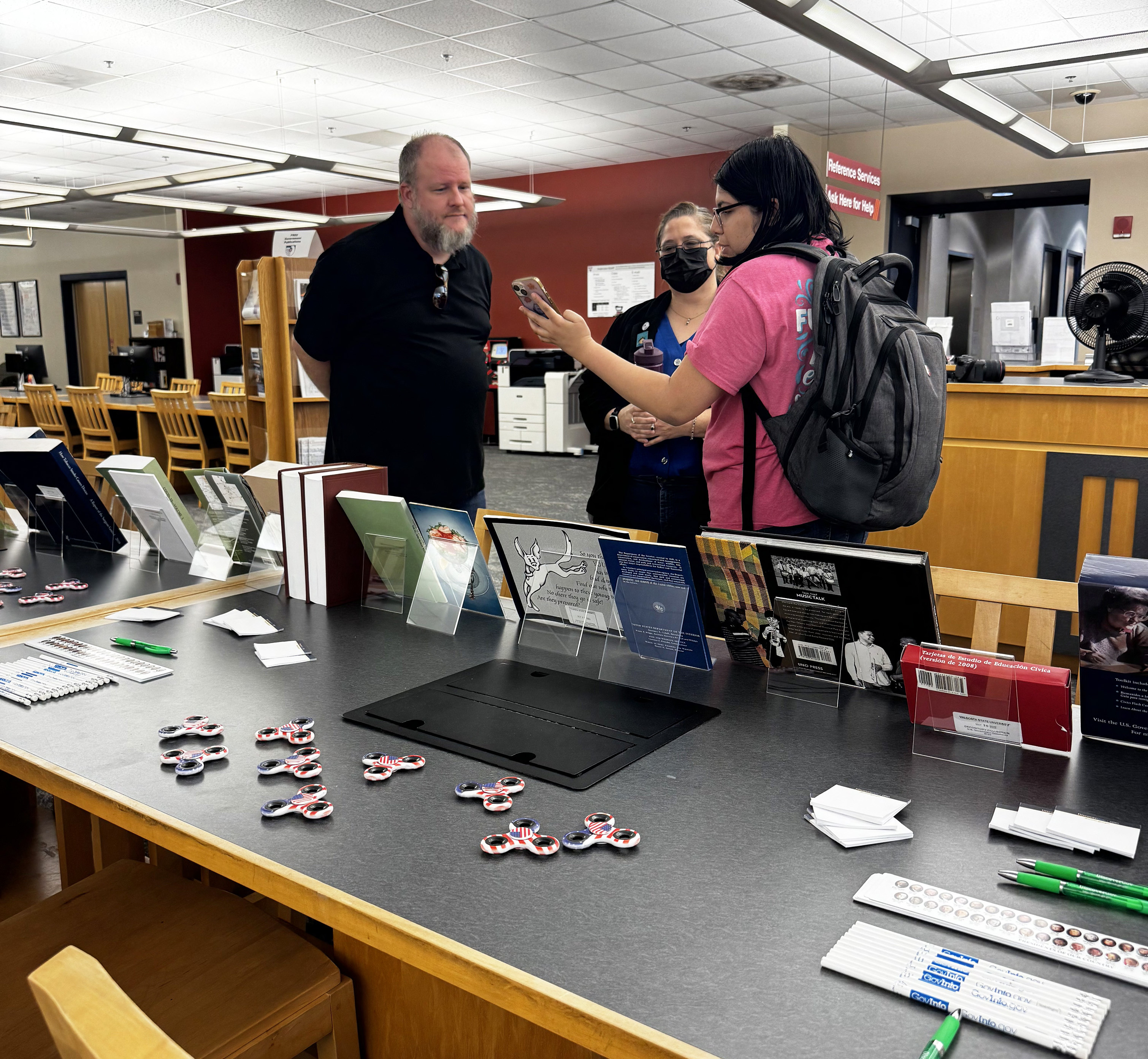 a group of people chatting near the library reference desk