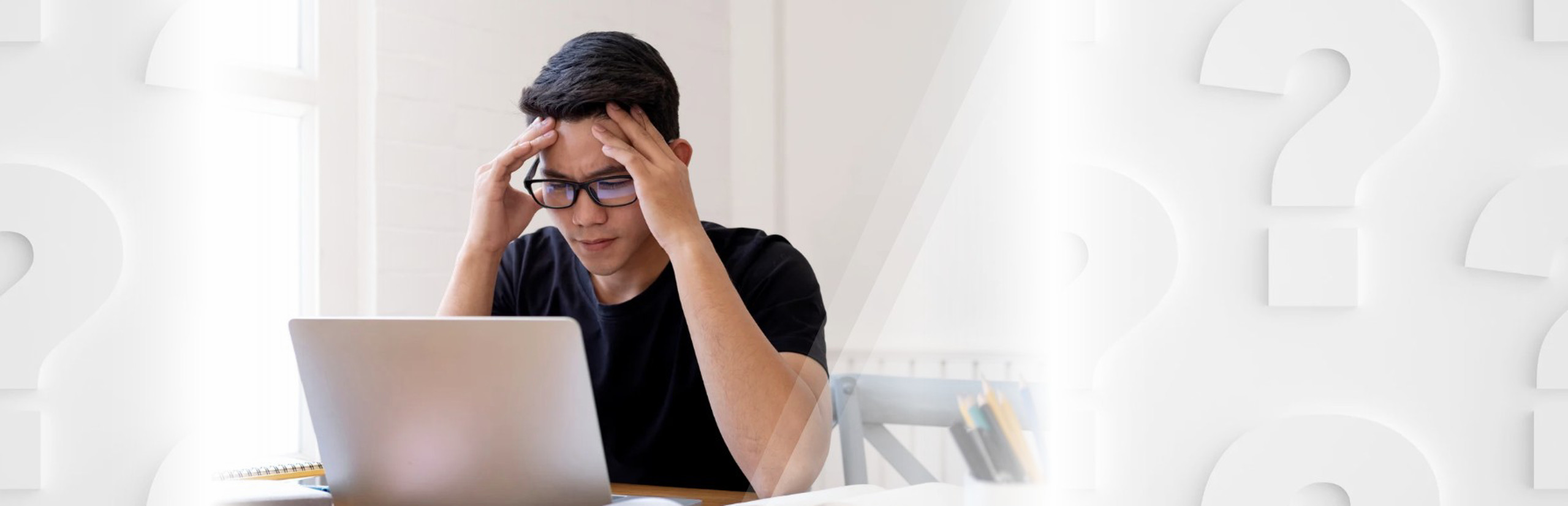Person wearing glasses holds their head while looking at a laptop, with large question marks in the background.