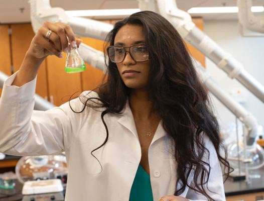 VSU student researcher holding beaker with green liquid