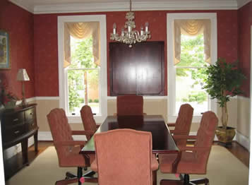 A long wooden table with chairs placed about it orderly.